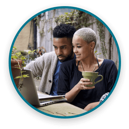 Woman and man sitting at an outdoor table and looking at information on a laptop