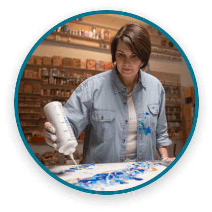 Woman applying paint to a canvas using a paint bottle