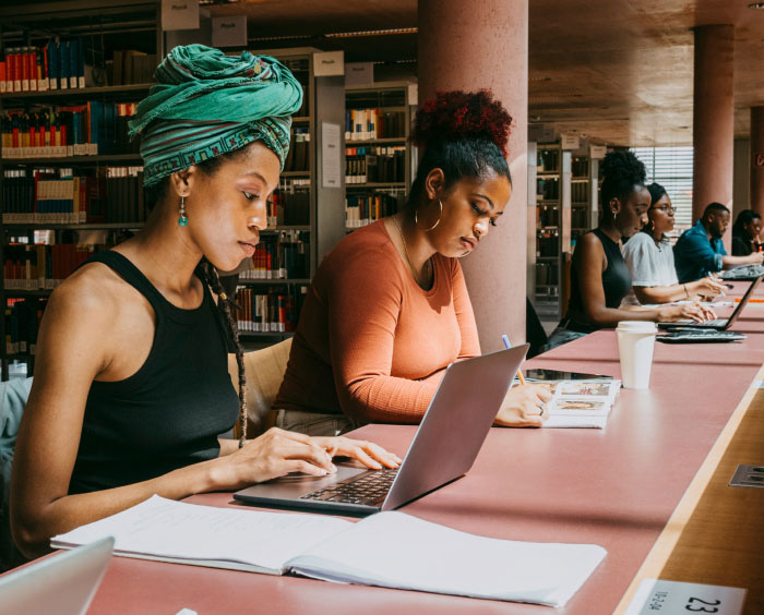 Woman using a laptop in a library, sitting at a desk